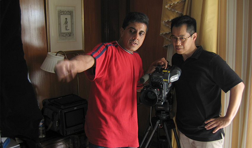 Arthur Dong stands behind a video camera and to the right of Allan Barrett